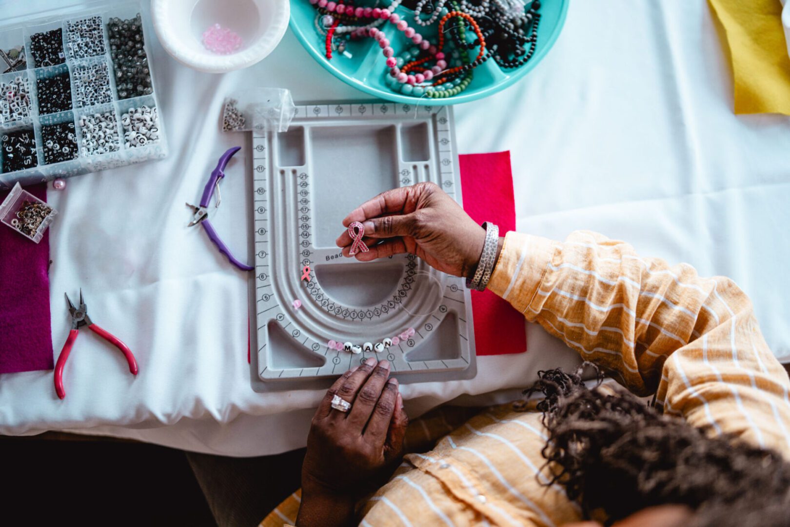 Hands creating beaded bracelet design